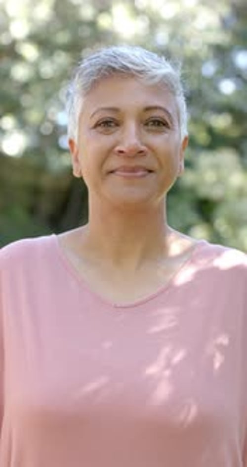 Vertical video of portrait of happy senior biracial woman in garden, slow motion