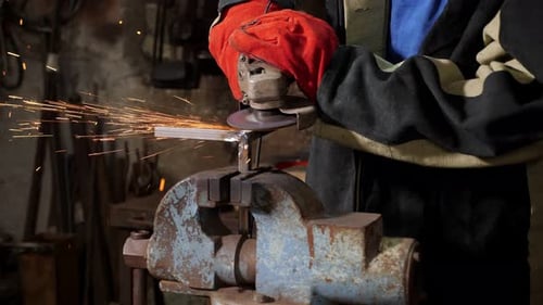 Closeup of a Blacksmith Man Working with a Metal Grinder in a Forge