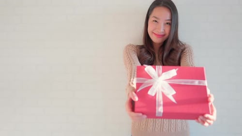 Young Woman Smiling and Holding Out Red Gift