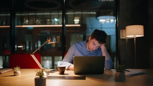 Man Using Laptop in Dark Office at Night