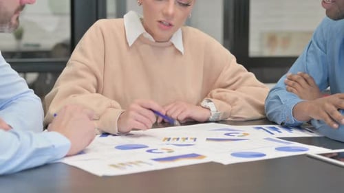 Colleagues Review Data at Table in Office