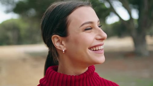 Joyful Cheerful Girl Laughing Happily Standing On Nature Wearing Red Sweater Close Up. Portrait O...