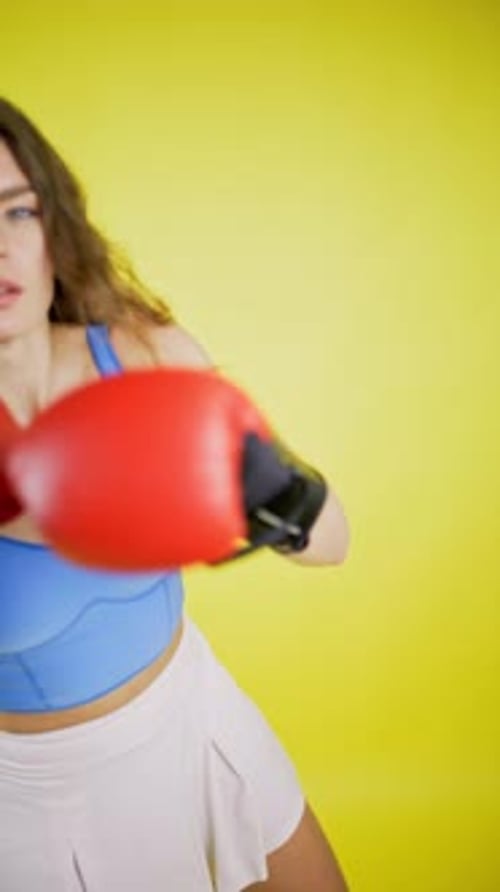 Attractive Woman Boxing with Red Gloves on Yellow Background