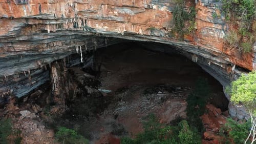 Aerial drone medium dolly out shot of the large Lapa Doce cave entrance of colorful rocks with a sel