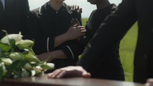 Mourners Gather at Graveside with Casket and Lilies