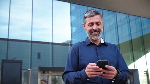 Real Mature Male Worker Watching a Finance App on His Cellphone Middle Aged Person Holding a Mobile