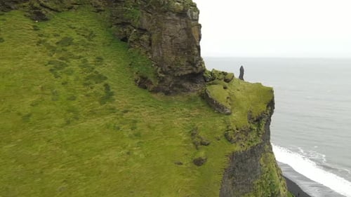 Black sand beach with towering sea stacks under a cloudy sky in Iceland,