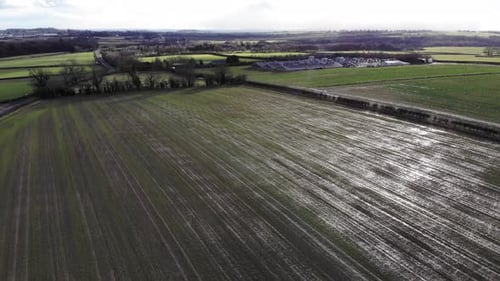 Aerial drone footage flying across a farmers field plowed and planted with new crops showing acres