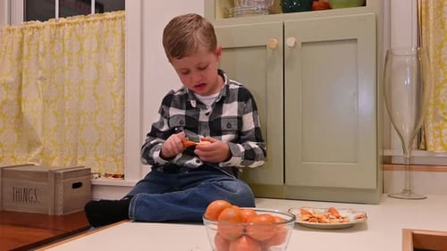 Boy Peels Tangerine in Kitchen