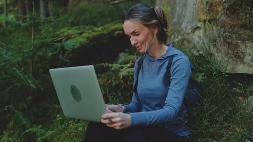 Woman Using Laptop in Forest Wilderness Setting