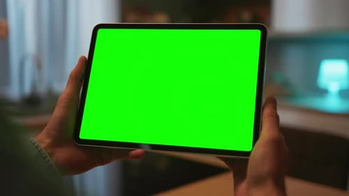 Man's Hand Holding Digital Tablet with Green Screen Chromakey on Blurred Background of Modern