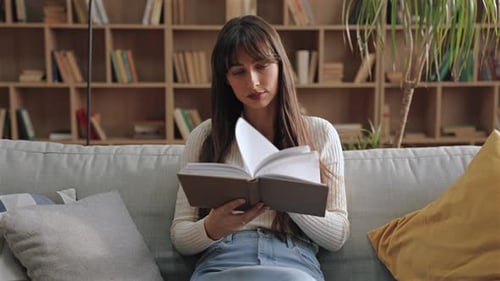 Woman Reading Book on Sofa in Cozy Home