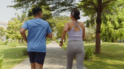 Sporty Couple Running in Park, Back View
