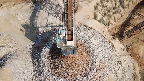large Quarry during work hours with Stone sorting conveyor belts and an open pit mine.
