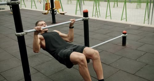 Young athletic man exercising outdoors and pull up on horizontal bar