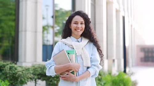 Smiling Student with Books Poses Near School