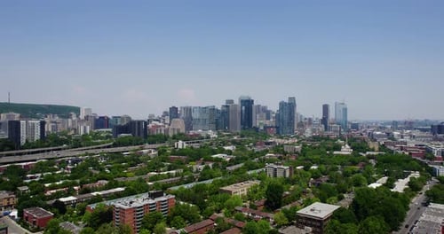 Drone shot ascending in front of suburbs and the downtown skyline of sunny Montreal