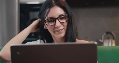 Woman Smiles at Laptop at Home