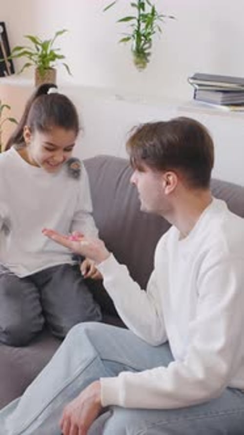 Child Styling Hair of Young Adult Indoors on Sofa