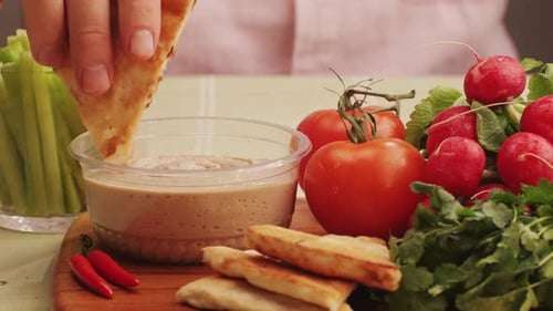 Fresh Vegetables and Pita Bread Being Dipped