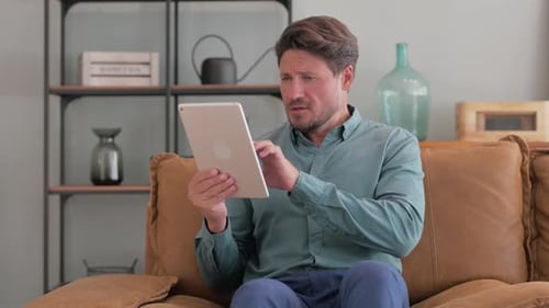 Excited Man Using Tablet Device on Couch