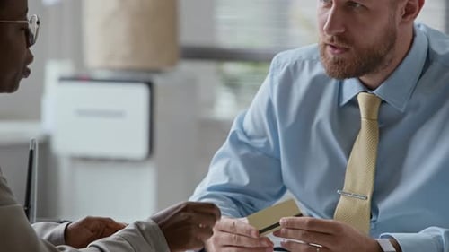 Female Client Listening to Manager Consulting about Credit Card in Bank Office