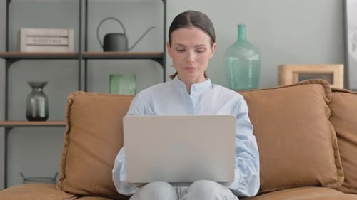 Woman Works on Laptop at Home on Couch