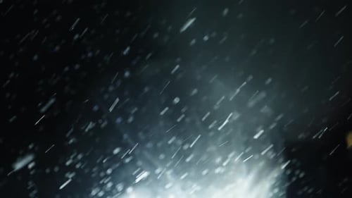Falling snow at night with bright light shining through