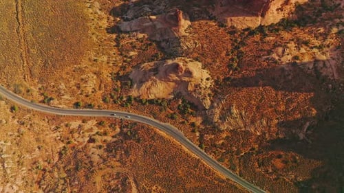 Two cars riding by the highway going through the desert landscape.