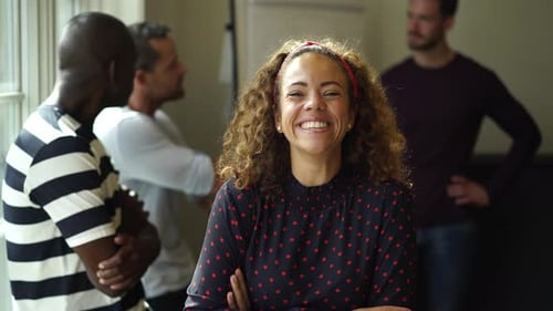 Confident young businesswoman laughing in a modern office with diverse coworkers