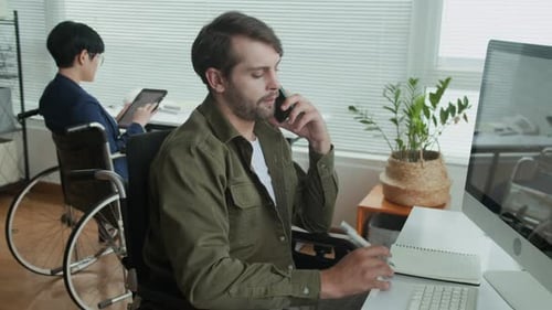 Young Manager with Disability Calling on Phone at Office with Colleague