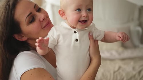 Happy Mother Holding Cute Smiling Baby Indoors