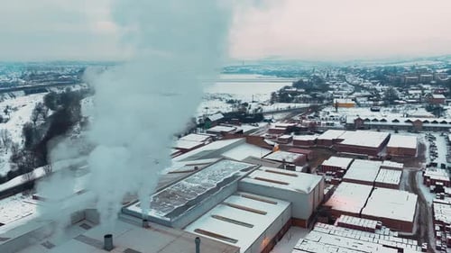 Aerial view of industrial factory emitting smoke in winter