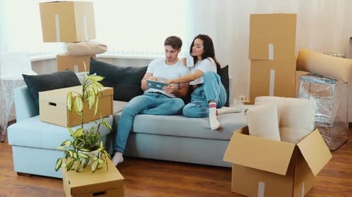 Couple Relaxing on Sofa with Tablet After Moving
