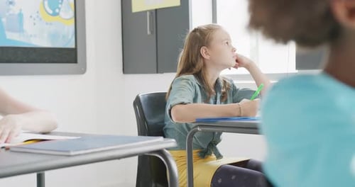 Video of bored caucasian schoolgirl sitting at desk looking out of window in class, copy space