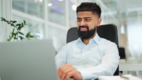 Man Video Conferencing on Laptop in Bright Office