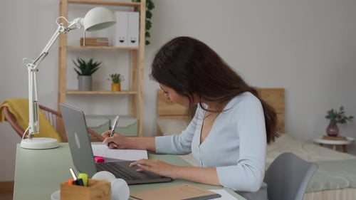 Woman Studies at Desk, Writing in Notebook