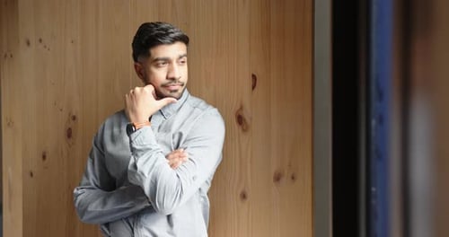 Business professional in office, thinking and looking out window, wearing smartwatch