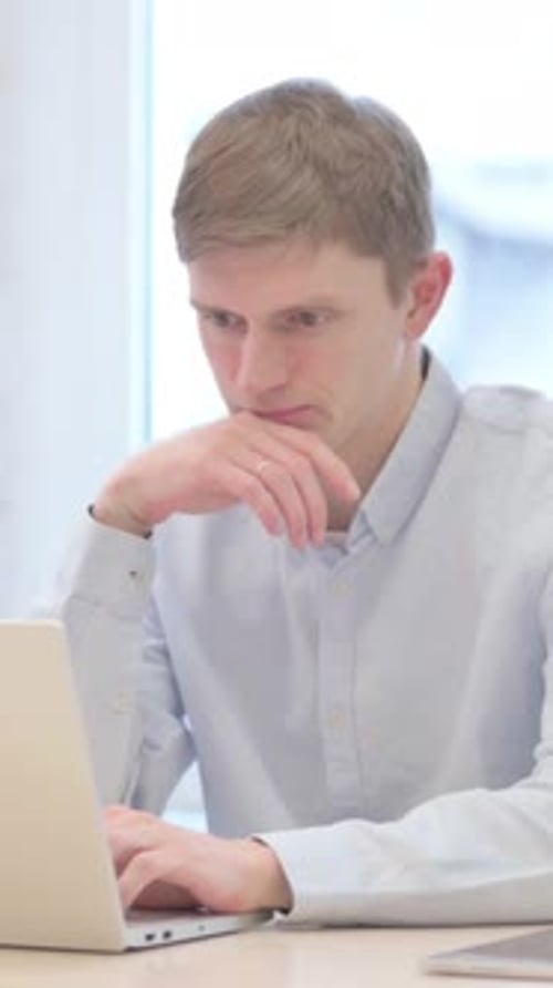 Man Works on Laptop in Bright Indoor Setting