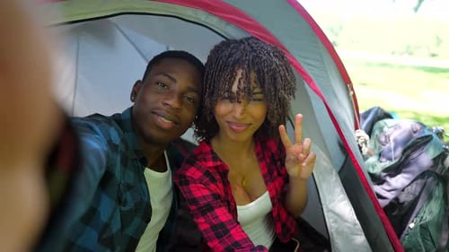Glückliches Paar macht während des Campingausflugs Selfies im Zelt