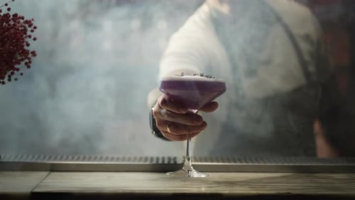 El camarero pone el cóctel decorado terminado en la barra del bar