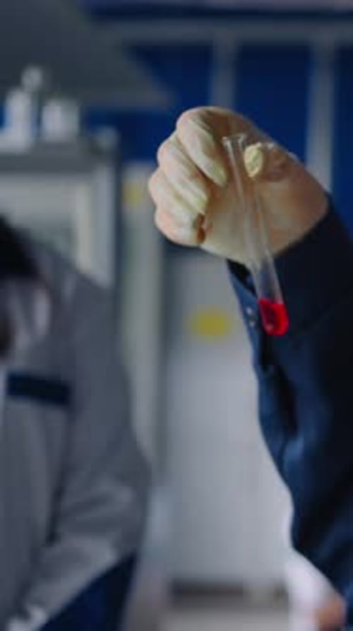 Científico examina un líquido rojo en un tubo de ensayo transparente durante un experimento de laboratorio que demuestra