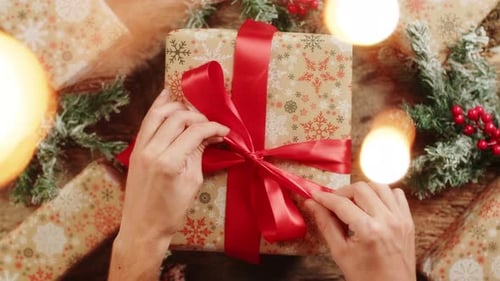 Person Unties Red Ribbon on Christmas Present