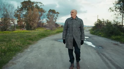 Elderly Man Walking on a Dirt Road During Winter