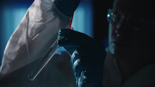 Un investigador forense añade una muestra de sangre a un tubo de ensayo con un reactivo utilizando una pipeta Un hombre