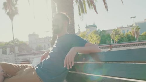 Man relaxing on park bench on sunny day