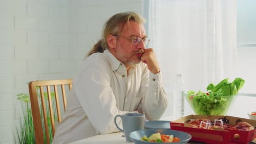 Thoughtful Man Sitting at Table with Food
