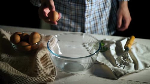 Man Hand Breaks Chicken Egg in Bowl. Chicken Egg Falls Into Glass
