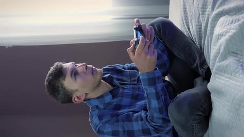 Young Adult Playing Video Game on Bed