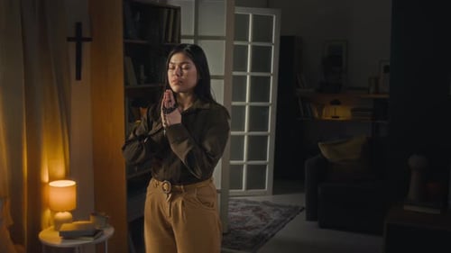 Woman Praying with Rosary Beads at Home